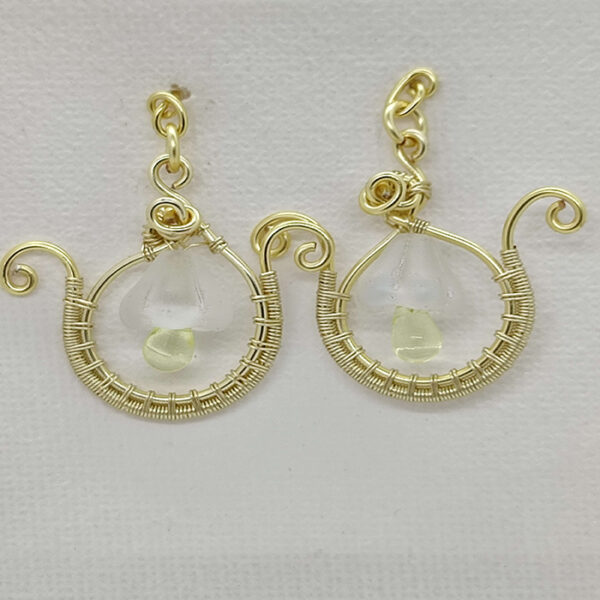 Boucles d'oreilles en fil de cuivre doré enroulé, de forme ronde. Une Perle goute en verre jaune suspendu à une perle en Christale mat au centre du bijoux